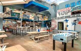 A lively outdoor setup with picnic tables, foosball, and bar seating creates the perfect gathering spot.